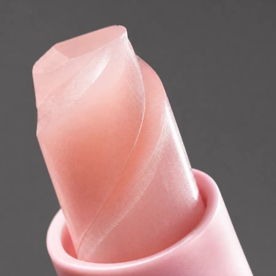 Macro photograph of the pale pink balm core twisted up above the rim of the open medicube stick