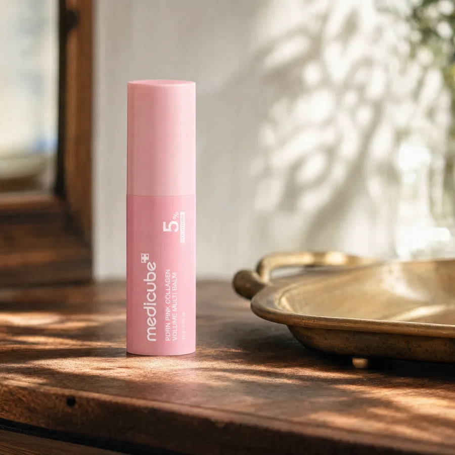The medicube balm stick standing on a wooden vanity beside a brass tray in dappled morning light