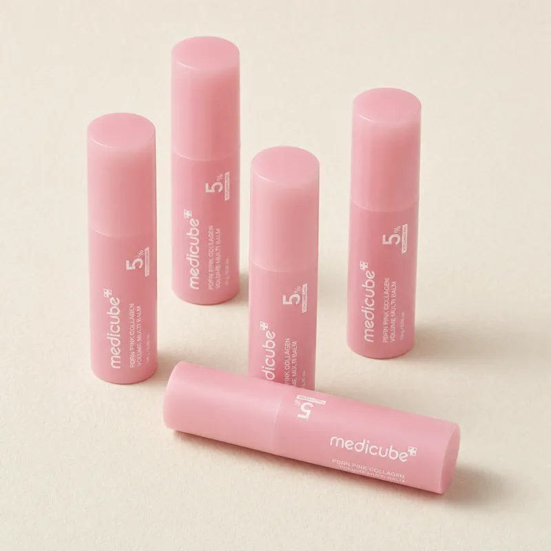 Five medicube PDRN Pink Collagen Volume Multi Balm sticks on a cream backdrop, four standing and one lying in front