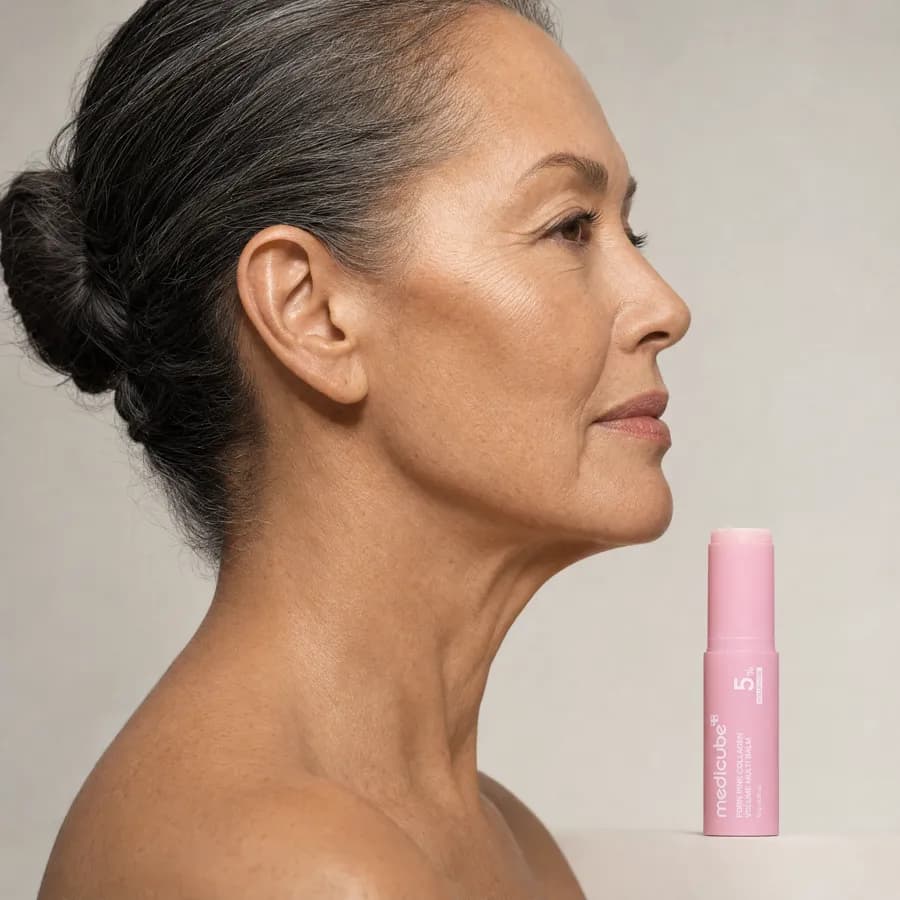 Profile of a woman beside the medicube balm stick, showing the cheek, jaw and neck the balm is formulated for