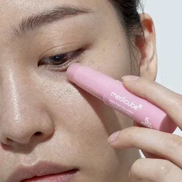The balm stick gliding over the under-eye area in one slow stroke